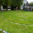 Spirallabyrinth Verden Spiralförmiges Labyrinth auf einer grünen Wiese, umgeben von Schildern und Bäumen in Verden.