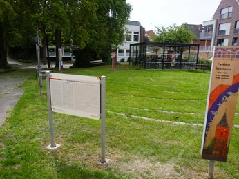 Spirallabyrinth Verden Eingebettet in eine grüne Rasenfläche, unwinden sich sanfte Steinkreise neben einem modernen Glasgebäude.