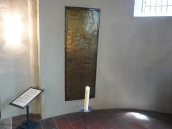 Bronzene Gedenktafel im Inneren der St. Andreaskirche, neben einem informativen Textständer.