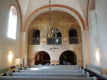 St. Andreaskirche Innenansicht der St. Andreaskirche: Ein mit Kronleuchter beleuchtetes Kirchenschiff aus Naturstein.