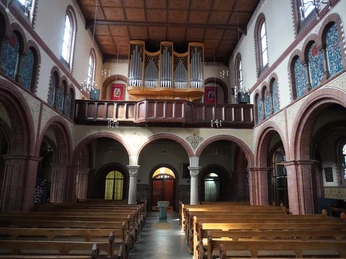 Innenansicht der St. Josefkirche Verden mit romanischen Bögen, Orgel und Holzbänken im Kirchenschiff.