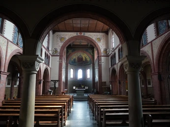 Blick in das Kircheninnere der St. Josefkirche in Verden mit Bankreihen und kunstvollem Altarfresko.