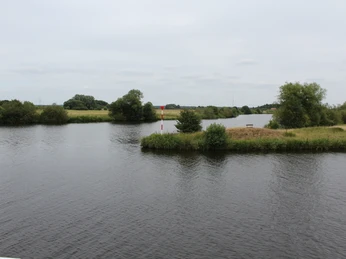 Allermündung Blick auf die Mündung der Aller, umgeben von grünen Uferböschungen und durchbrochen von ruhigem Wasser.