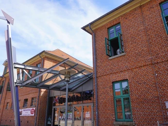 Stadthalle Verden Das Bild zeigt die Fassade der Stadthalle Verden mit roten Backsteinen und grünen Fensterrahmen.