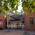 Stadthalle Verden Eingang der Stadthalle Verden mit Glasfassade und rotem Ziegelbau, umrahmt von Kastanienblättern.