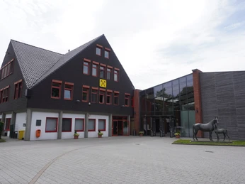 Niedersachsenhalle Verden Niedersachsenhalle Verden mit modernem Anbau und Pferdestatue im Vordergrund unter bewölktem Himmel.