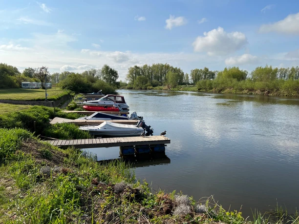 Wassersportverein Verden Bootsanleger am Ufer der Verden, umgeben von grüner Vegetation und dem ruhigen Wasser der Aller.