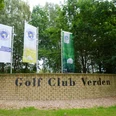 Golfplatz Verden Eingang zum Golf Club Verden mit drei Fahnen und einer Steinmauer in grüner, lauschiger Umgebung.