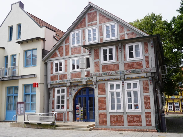 Half-timbered building of the Verden tourist information office with white windows and blue entrance under a cloudy sky.