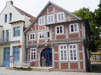 Tourist-Info Verden Fachwerkgebäude der Tourist-Info Verden mit weißen Fenstern und blauem Eingang unter bewölktem Himmel.Half-timbered building of the Verden tourist information office with white windows and blue entrance under a cloudy sky.Verden Tourist Information Centers bindingsværksbygning med hvide vinduer og blå indgang under en overskyet himmel.Vakwerkgebouw van het Verden Tourist Information Centre met witte ramen en blauwe ingang onder een bewolkte hemel.