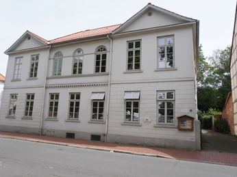 Ehem. Wohnhaus Anita Augspurg Verden Zweigeschossiges, helles Gebäude in Verden mit vielen Fenstern und einem roten Ziegeldach.