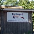Holzgebäude mit Schild des Kletterparks Verden, umgeben von Bäumen, bietet Abenteuer und Natur.Wooden building with sign of the Verden climbing park, surrounded by trees, offers adventure and nature.Træbygning med skilt til Verden klatrepark, omgivet af træer, byder på eventyr og natur.Houten gebouw met uithangbord van klimpark Verden, omgeven door bomen, biedt avontuur en natuur.