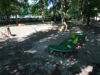 Kletterpark Verden Minigolfbahn im Schatten hoher Bäume in einem Waldgebiet, mit gelben Hindernissen und natürlichem Umfeld.Minigolf course in the shade of tall trees in a wooded area, with yellow obstacles and natural surroundings.Minigolfbane i skyggen af høje træer i et skovområde, med gule forhindringer og naturlige omgivelser.Minigolfbaan in de schaduw van hoge bomen in een bosrijke omgeving, met gele hindernissen en een natuurlijke omgeving.