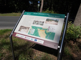 Informationsschild am Waldrand informiert über die Verdener Dünen und zeigt Karten- sowie Fotomaterial.