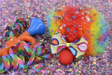 Karneval in Bad Driburg Buntes Karnevalszubehör, inklusive Clownsperücke, Tröte und Schleife, umgeben von Konfetti.