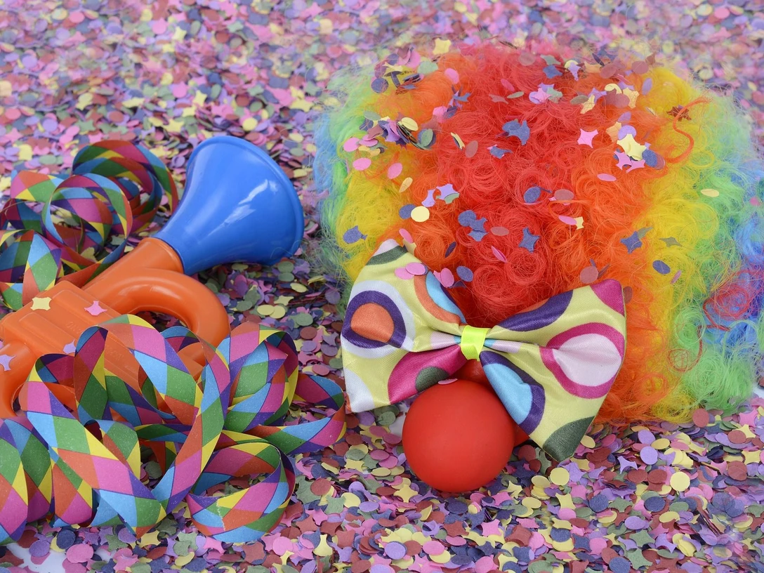 Karneval in Bad Driburg Buntes Karnevalszubehör, inklusive Clownsperücke, Tröte und Schleife, umgeben von Konfetti.