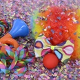 Karneval in Bad Driburg Buntes Karnevalszubehör, inklusive Clownsperücke, Tröte und Schleife, umgeben von Konfetti.