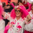 Karneval in Bad Driburg Eine Person in pinker Flamingo-Kleidung tanzt fröhlich auf einem Karnevalsumzug, umgeben von Feiernden.