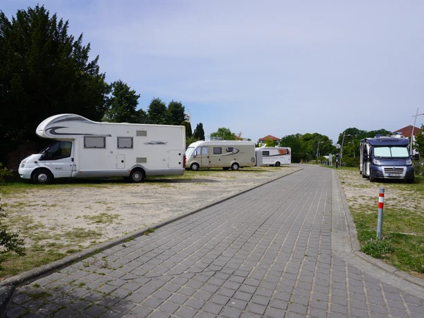 Wohnmobilstellplatz Verden Ruhiger Stellplatz mit gepflastertem Weg und mehreren geparkten Wohnmobilen in grüner Umgebung.