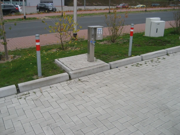 Wohnmobilstellplatz Verden Wohnmobilstellplatz mit gepflastertem Boden, Stromsäule und umgebender Straße in urbaner Umgebung.