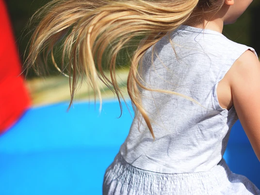 Kinderfest Junge Mädchen mit flatternden Haaren im weißen Kleid beim fröhlichen Spielen vor buntem Hintergrund.Young girl with fluttering hair in a white dress playing happily in front of a colorful background.Jong meisje met wapperend haar in een witte jurk speelt vrolijk voor een kleurrijke achtergrond.Ung pige med flagrende hår i hvid kjole leger lykkeligt foran en farverig baggrund.
