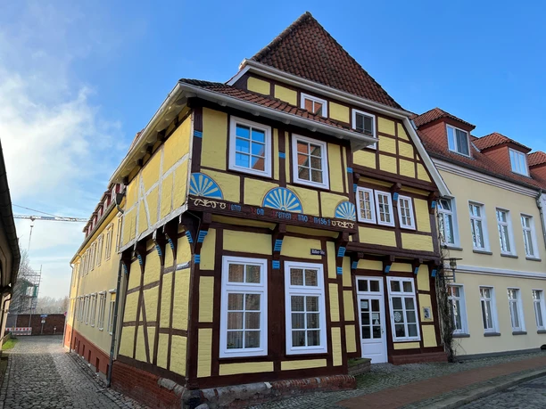 Fachwerkhaus mit gelber Fassade und blauen Akzenten, historisch und prägend für die Straße.