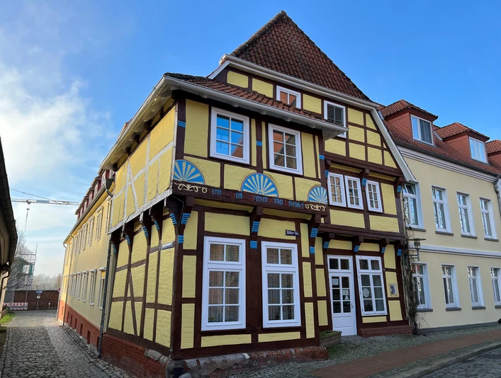 Fachwerkhaus mit gelber Fassade und blauen Akzenten, historisch und prägend für die Straße.