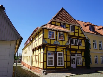 Fachwerkhaus von 1561 mit dekorativen Holzdetails und roten Ziegeln, unter blauem Himmel.