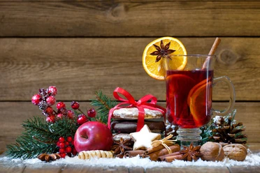 Weihnachten Ein Glas Glühwein mit Zimt, Orange und Sternanis, umgeben von weihnachtlichen Leckereien.