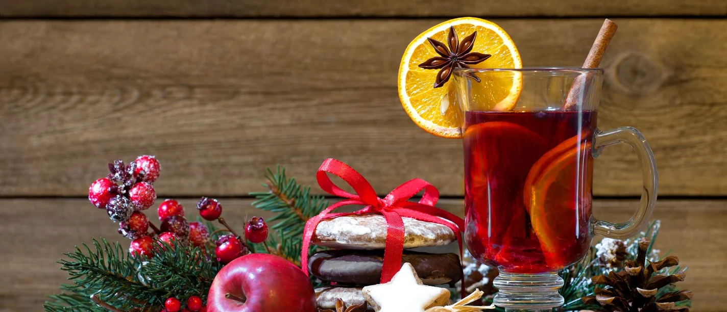 Weihnachten Ein Glas Glühwein mit Zimt, Orange und Sternanis, umgeben von weihnachtlichen Leckereien.