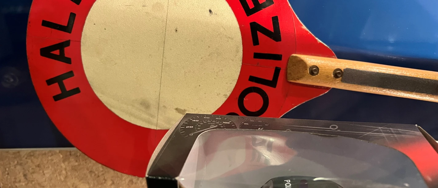 Polizei Ein altes Polizeischild mit einem Miniaturmodell eines grünen VW Käfer Polizeiautos im Vordergrund.