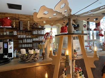 Pult kavárny Welyn Gemütlich dekorierter Tresen mit Weihnachtsdekoration, darunter eine Holzpyramide mit Kerzen, ein Adventskranz und Figuren in einer warmen Atmosphäre.Cozy decorated counter with Christmas decorations, including a wooden pyramid with candles, an Advent wreath and figurines in a warm atmosphere.Útulně vyzdobený pult s vánočními dekoracemi, včetně dřevěné pyramidy se svíčkami, adventního věnce a figurek v příjemné atmosféře.Przytulnie udekorowana lada ze świątecznymi dekoracjami, w tym drewnianą piramidą ze świecami, wieńcem adwentowym i figurkami w ciepłej atmosferze.Gezellig ingerichte toonbank met kerstdecoraties, waaronder een houten piramide met kaarsen, een adventskrans en beeldjes in een warme sfeer.Bancone arredato in modo accogliente con decorazioni natalizie, tra cui una piramide di legno con candele, una corona dell'Avvento e statuine in un'atmosfera calda.