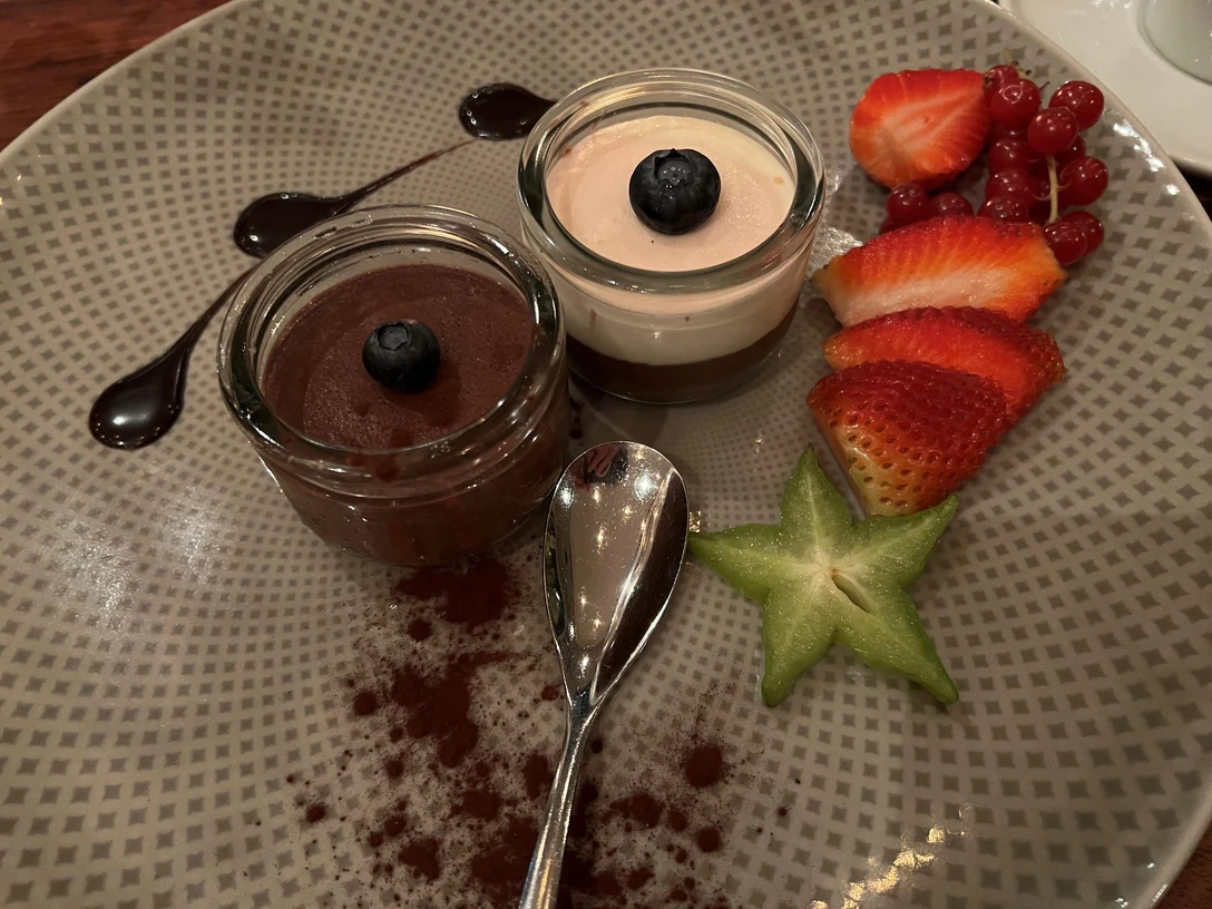 Dessert Zwei Dessertgläser mit Schokoladenmousse und Beeren auf einem kunstvoll angerichteten Teller.
