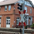 Ein rotes Backsteingebäude des Bahnhofs Bruchhausen-Vilsen mit charakteristischen weißen Fensterrahmen und einem Bahnübergangsschild im Vordergrund.