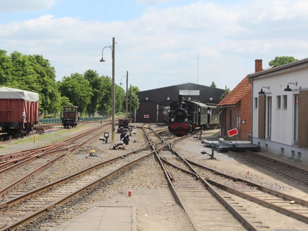Museumseisenbahn Bruchhausen-Vilsen Museumseisenbahn mit Dampflok und historischen Waggons auf Gleisanlage, umgeben von dichtem Grün.