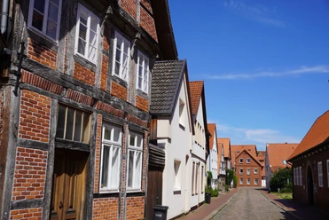 Historic half-timbered houses with traditional tiled roofs line a quiet cobbled street.