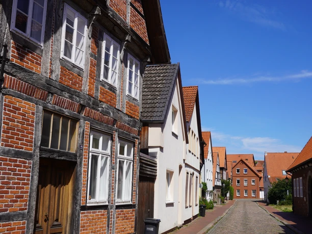 Fischerviertel Verden Historische Fachwerkhäuser mit traditionellen Ziegeldächern säumen eine ruhige gepflasterte Straße.