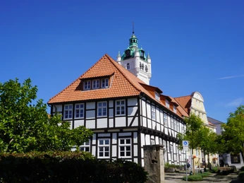 Blick auf Rathaus Verden Fachwerkhaus in Verden mit markantem Turm vor strahlend blauem Himmel und grünen Bäumen im Vordergrund.