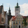 Historisches Rathaus von Verden mit weißem Turm und Uhr, umgeben von Fachwerkhäusern und Bäumen.