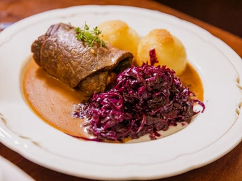 Roulades à l'Auerbachs Keller – L'art culinaire à Leipzig Une assiette avec une roulade, du chou rouge, des boulettes en sauce à l'Auerbachs Keller à Leipzig
