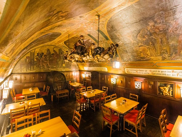 Historický sudový sklep Auerbachů Kellerů v Lipsku se stropními malbami a místo lustru obrovskou čarodějnickou jízdou vyřezanou z kmene stromu, kulinářské speciality, gastronomie.