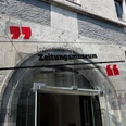 IZM Eingangstür mit rundem Bogen, über der ein gläsernes Schild mit dem Aufdruck "Internationales Zeitungsmuseum" befestigt ist.