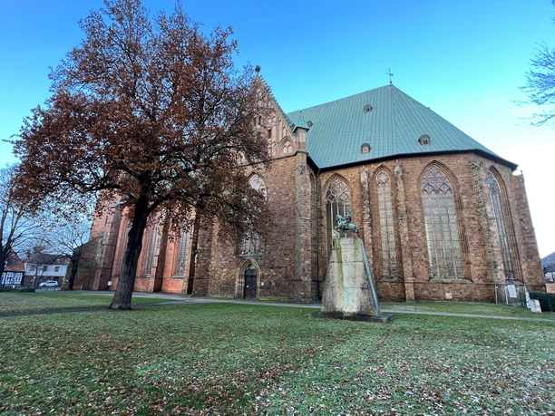 Dom Verden Der Dom in Verden mit grüner Kupferdachhaube und einem steinernen Reiterdenkmal im Vordergrund.