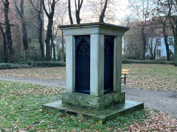 Bischofsdenkmal Verden Denkmal der Bischöfe von Verden, umgeben von Herbstlaub in einem ruhigen Park mit alten Bäumen.
