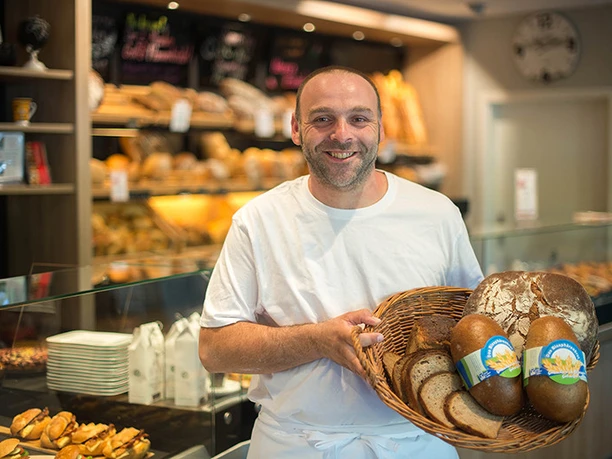 Bäcker mit Brotauswahl im Café Bäckerei Lenert, 2018, Manuela Meyer