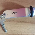 Ein Metallschlüsselanhänger mit der Nummer 3 und einem daran befestigten Schlüssel auf Holzoberfläche.