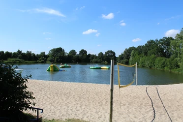 Naturfreibad Eystrup Sandstrand mit Volleyballnetz am Naturfreibad Eystrup. Im Wasser sind aufblasbare Spielgeräte.