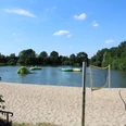 Naturfreibad Eystrup Sandstrand mit Volleyballnetz am Naturfreibad Eystrup. Im Wasser sind aufblasbare Spielgeräte.
