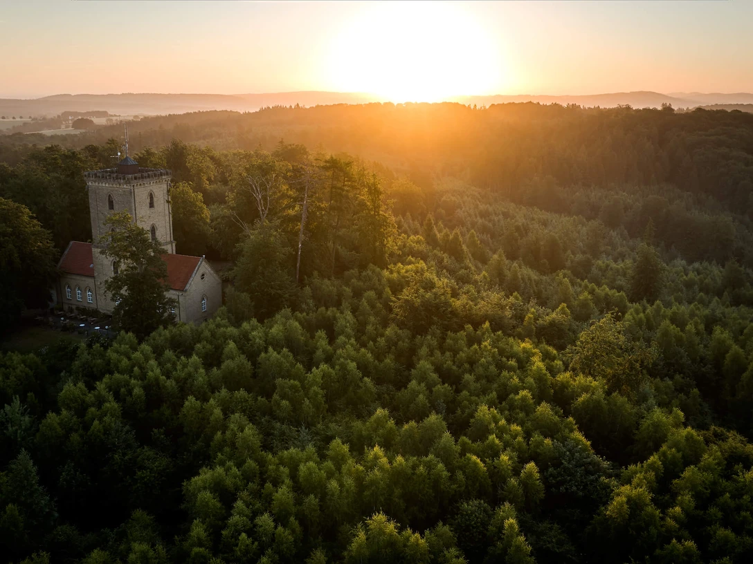 Die Diedrichsburg im Osnabrücker Land Ein steinerner Turm erhebt sich aus einem dichten Wald im Sonnenuntergang und bietet eine weite Aussicht.A stone tower rises out of a dense forest at sunset and offers a sweeping view.Et stentårn rejser sig ud af den tætte skov ved solnedgang og byder på en fantastisk udsigt.Een stenen toren rijst op uit een dicht bos bij zonsondergang en biedt een weids uitzicht.