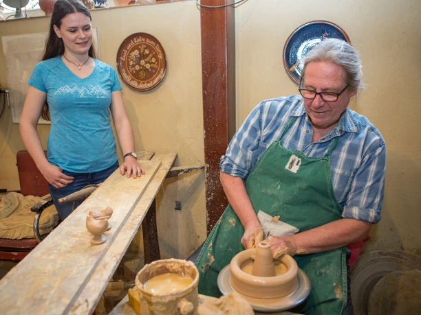 Töpfermeister Bernd Niehenke in Hasbergen Mann töpfert, während Frau interessiert zuschaut; traditionelle Handwerkskunst.